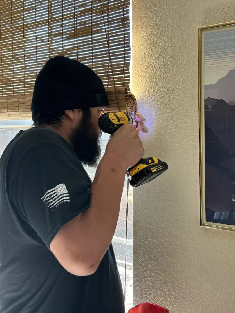 Man using drill to hang a picture.