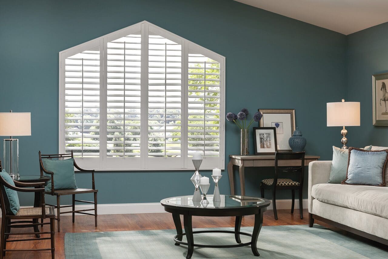 White shutters in arched window in living room.